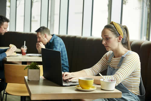 Woman working from busy cafe