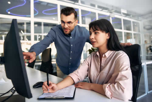 Office worker showing colleague how to use software