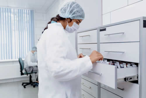 Laboratory worker retrieving supplies from labelled storage drawers